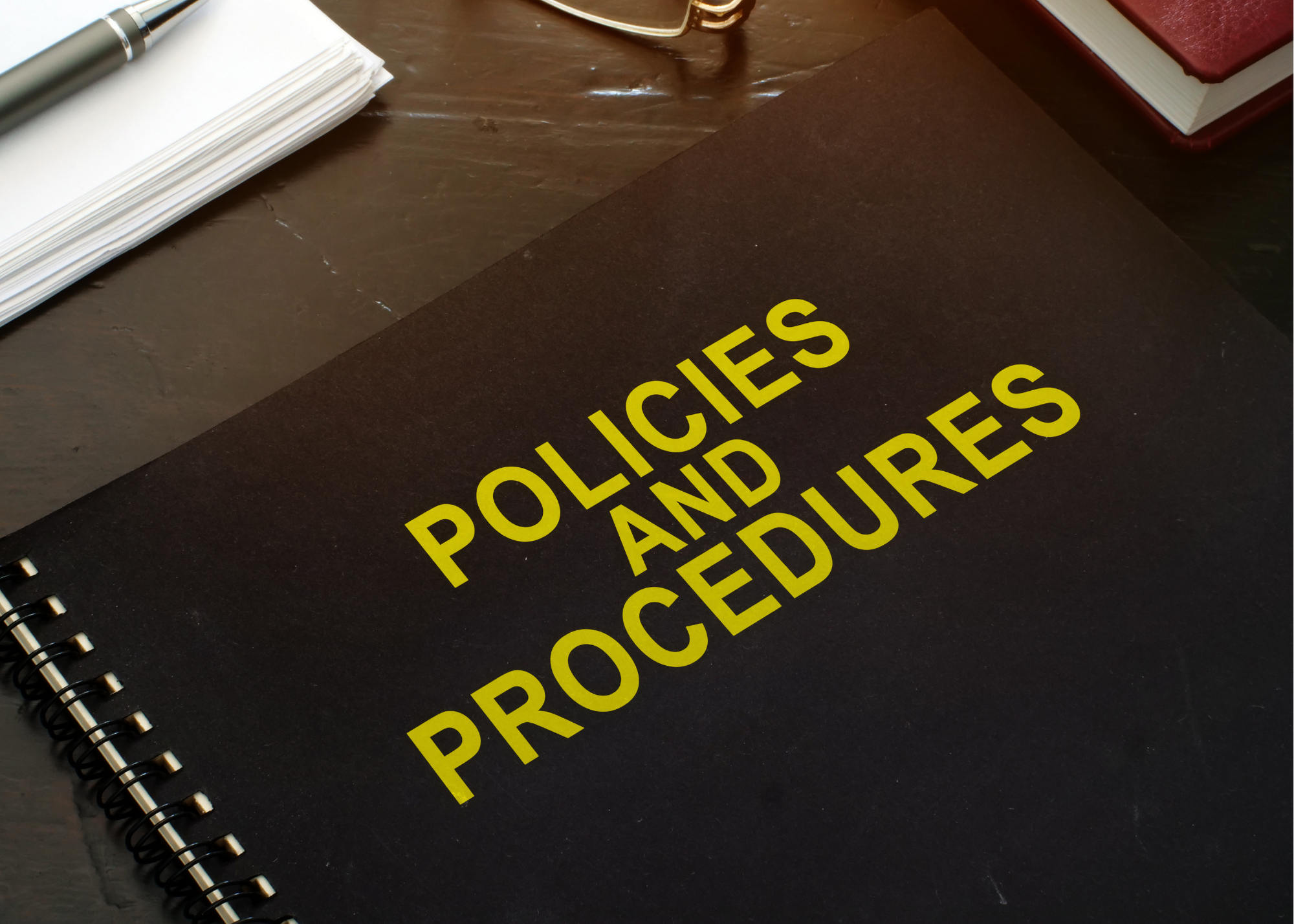 A notebook on a desk with the title "Policies and Procedures" on it.