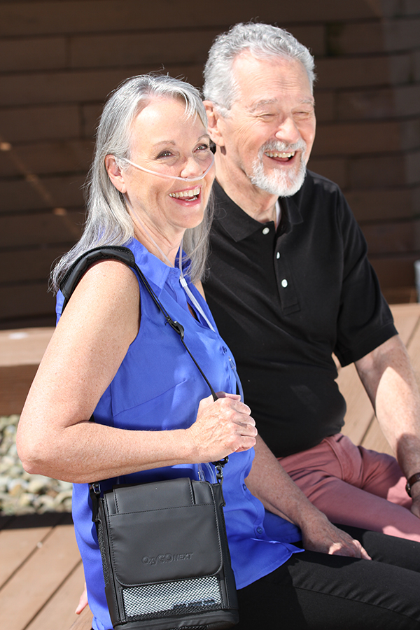 Older Couple laughing in the sun, one of them is on oxygen